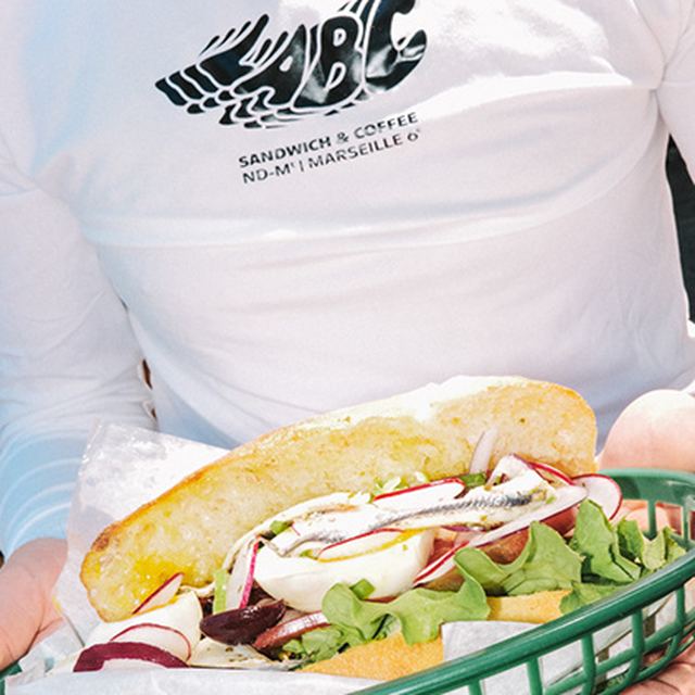 Sandwich servi en terrasse, tenu à deux mains